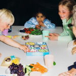 Børn omkring et bord med spil og snacks