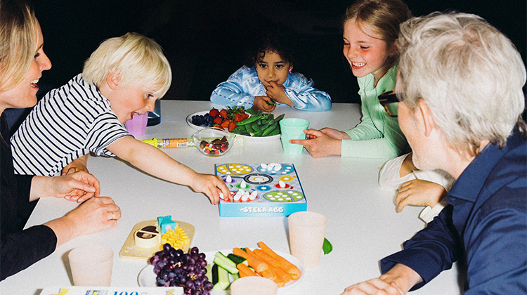 Børn omkring et bord med spil og snacks