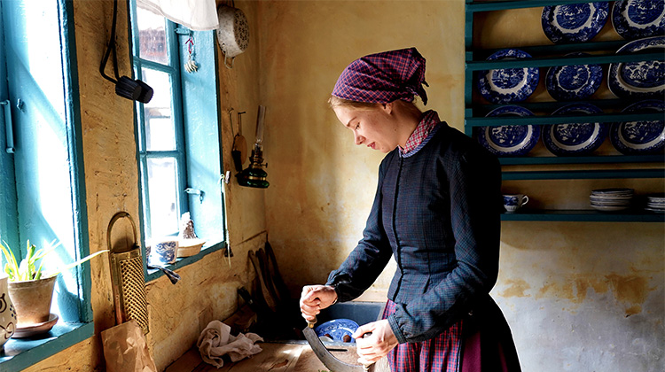Tjenestepige i Købmandsgaarden i Den Gamle By laver mad.