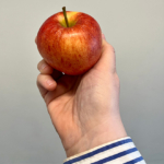 Æble i hånd på grå baggrund