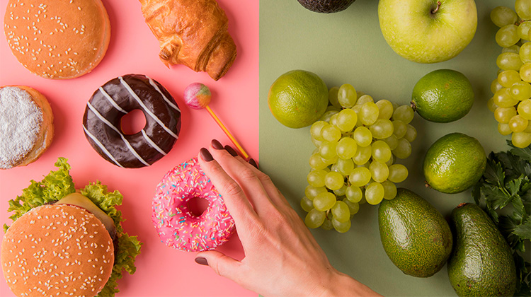 Usunde fristelser på den ene side - frugt og grønt på den anden. Hånd vælger en donut.
